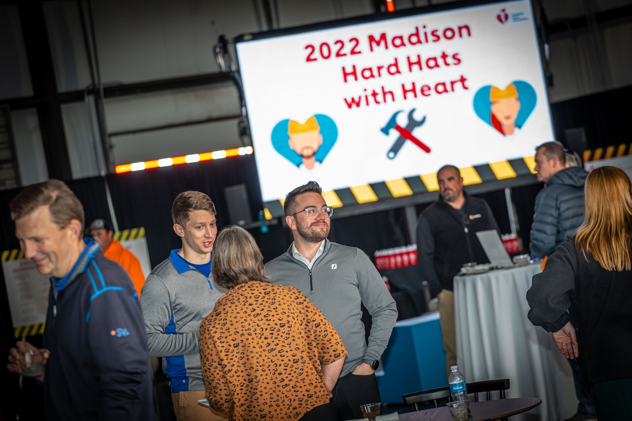 Picture of people standing in front of 2022 Madison Hard Hats with Heart sign